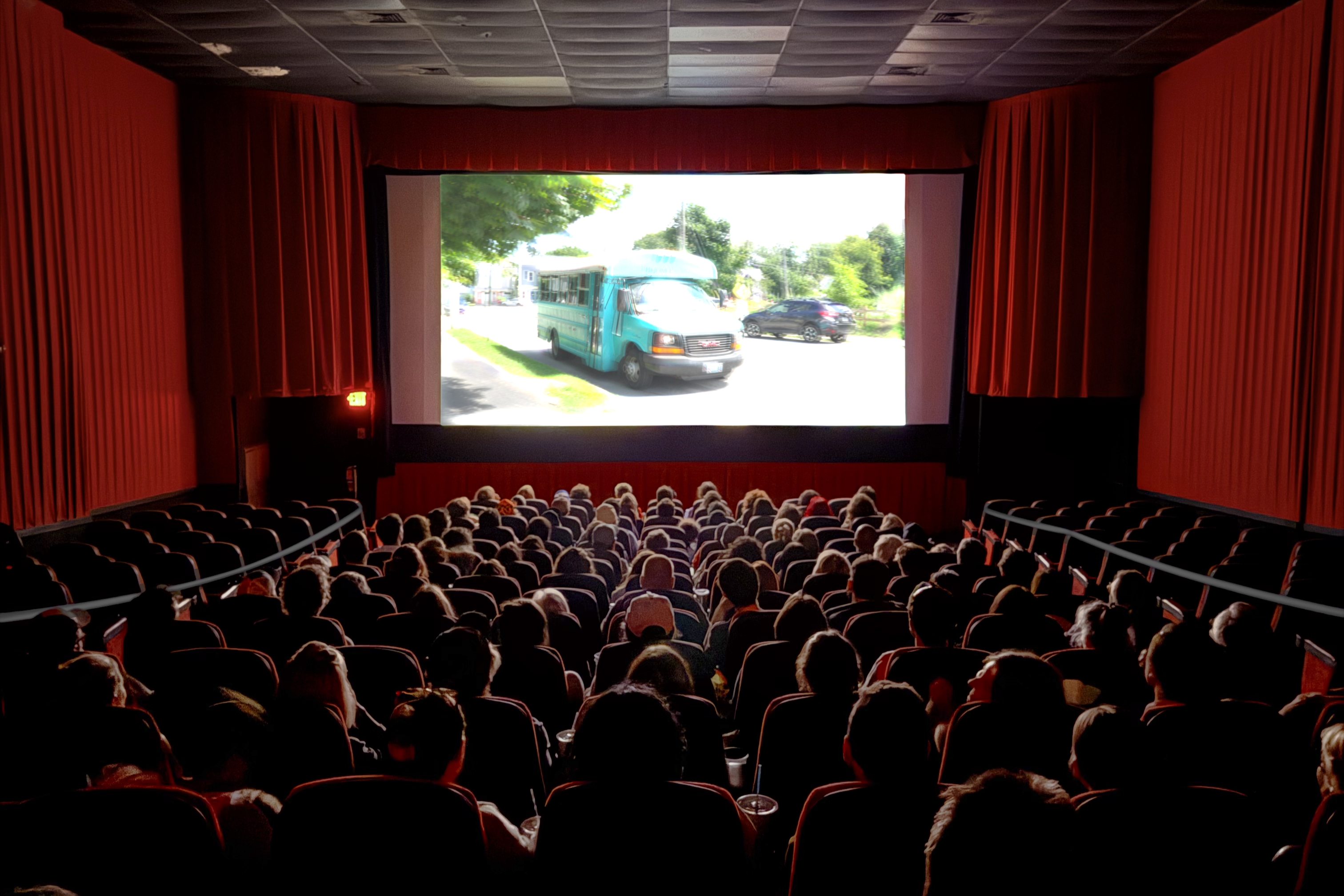 A packed theater at the Nickelodeon Cinemas in Portland, ME views 'Childish Things.' On screen is the iconic blue bus from the film.